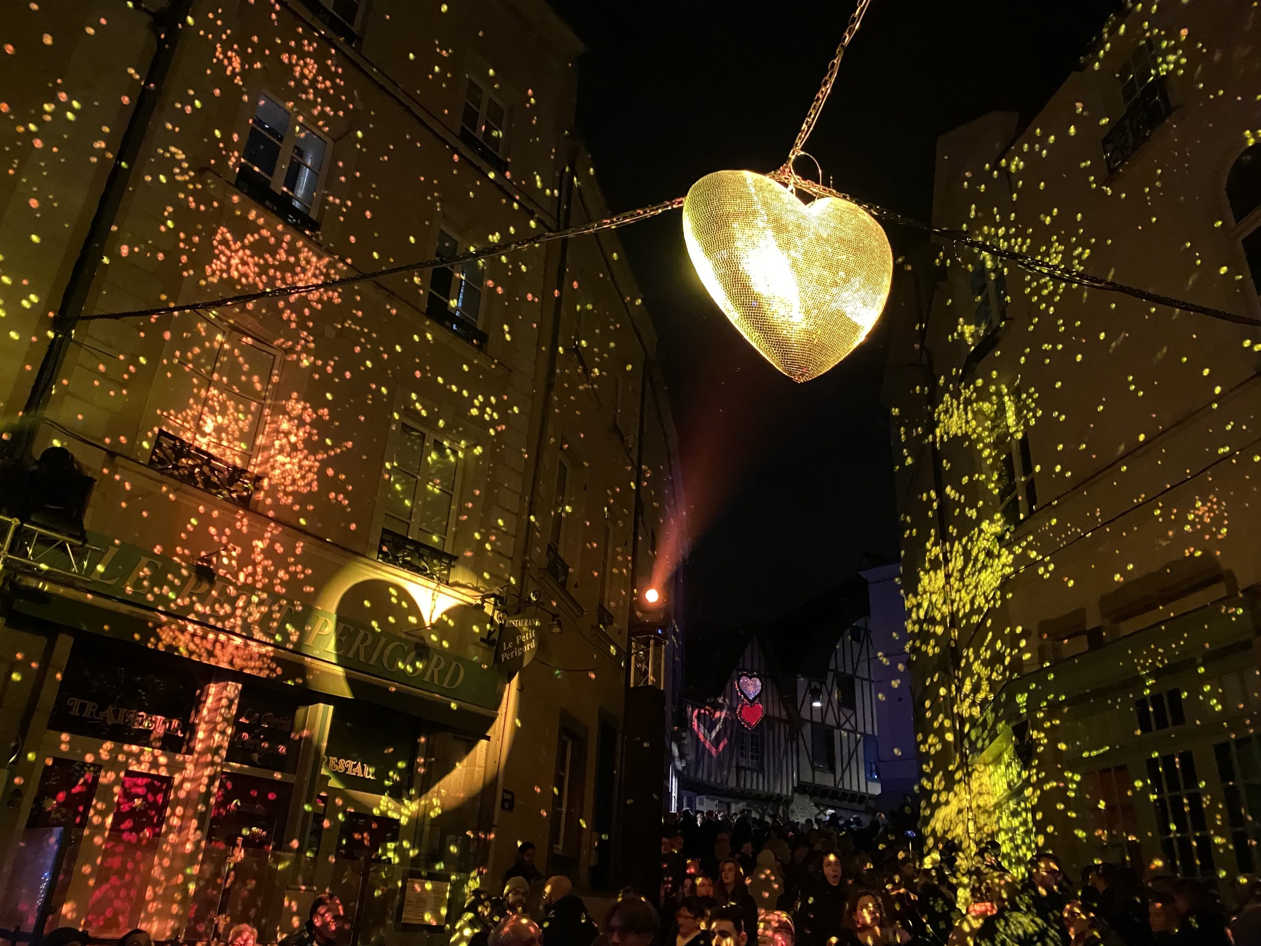 Le soir de Noël, cœur à facettes dans la nuit projetant des paillettes sur les murs de la ville